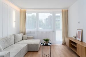 Bright minimalist living room in Kraków with modern decor, large windows, and natural light.